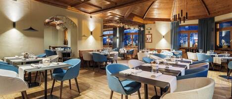 Un restaurante con vigas de madera en el techo, sillas azules y mesas dispuestas para comer.