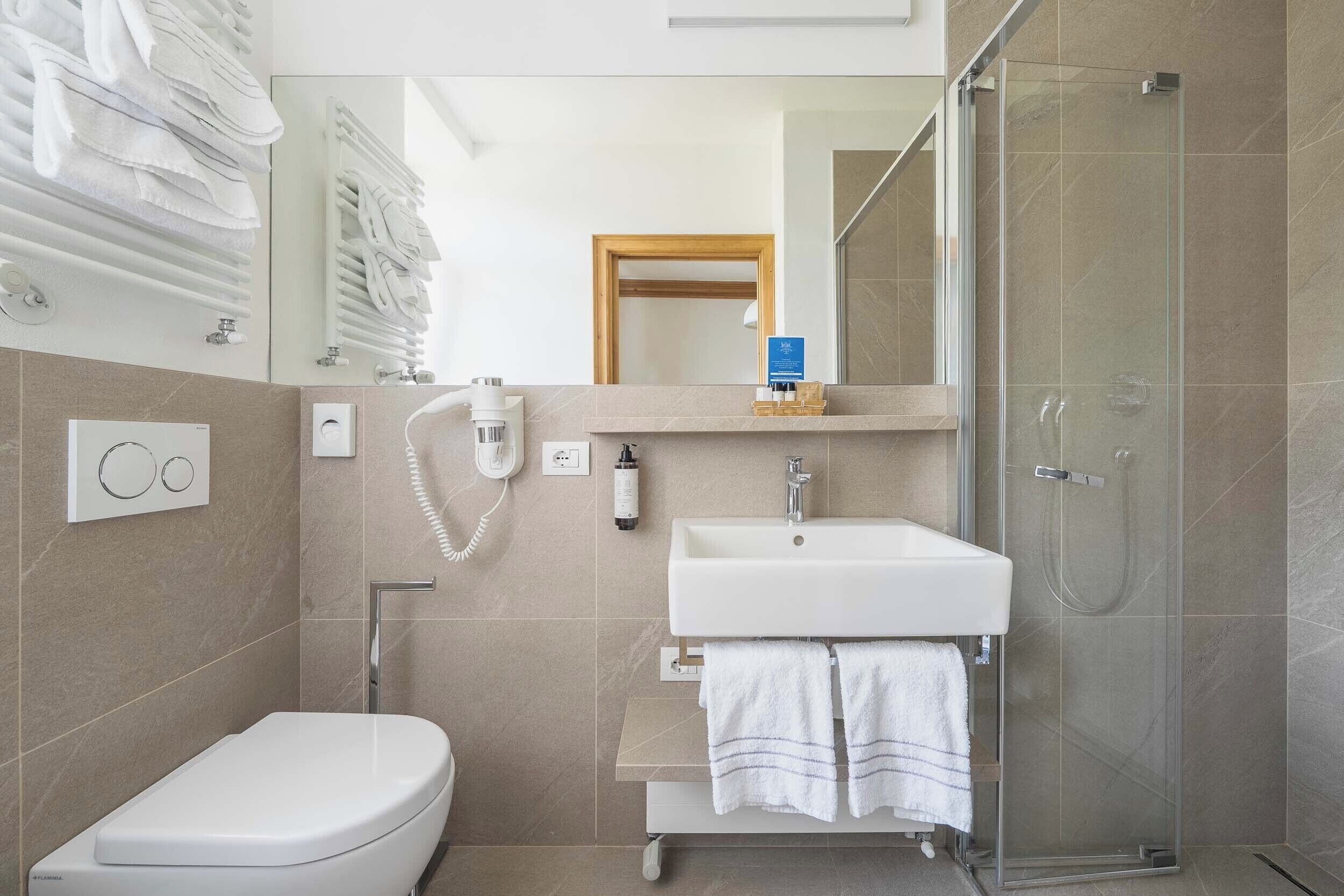 Un baño moderno con inodoro, lavamanos y ducha de vidrio.