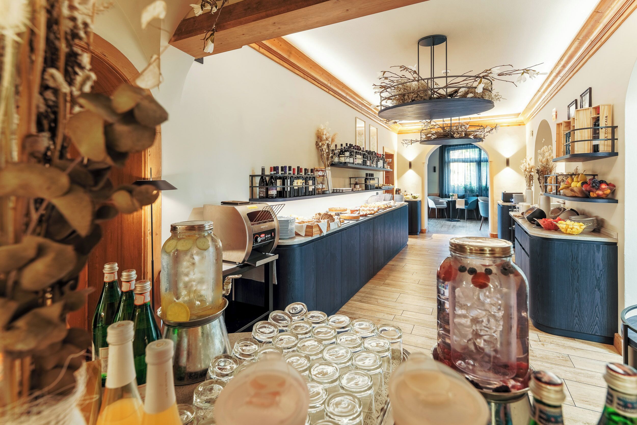 Zona de bar con mostrador, estantes llenos de botellas y una variedad de alimentos.