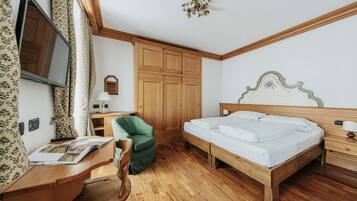 Ein Schlafzimmer mit einem hölzernen Bett, einem Schreibtisch mit Stuhl, einem Fernseher und einem Kleiderschrank.