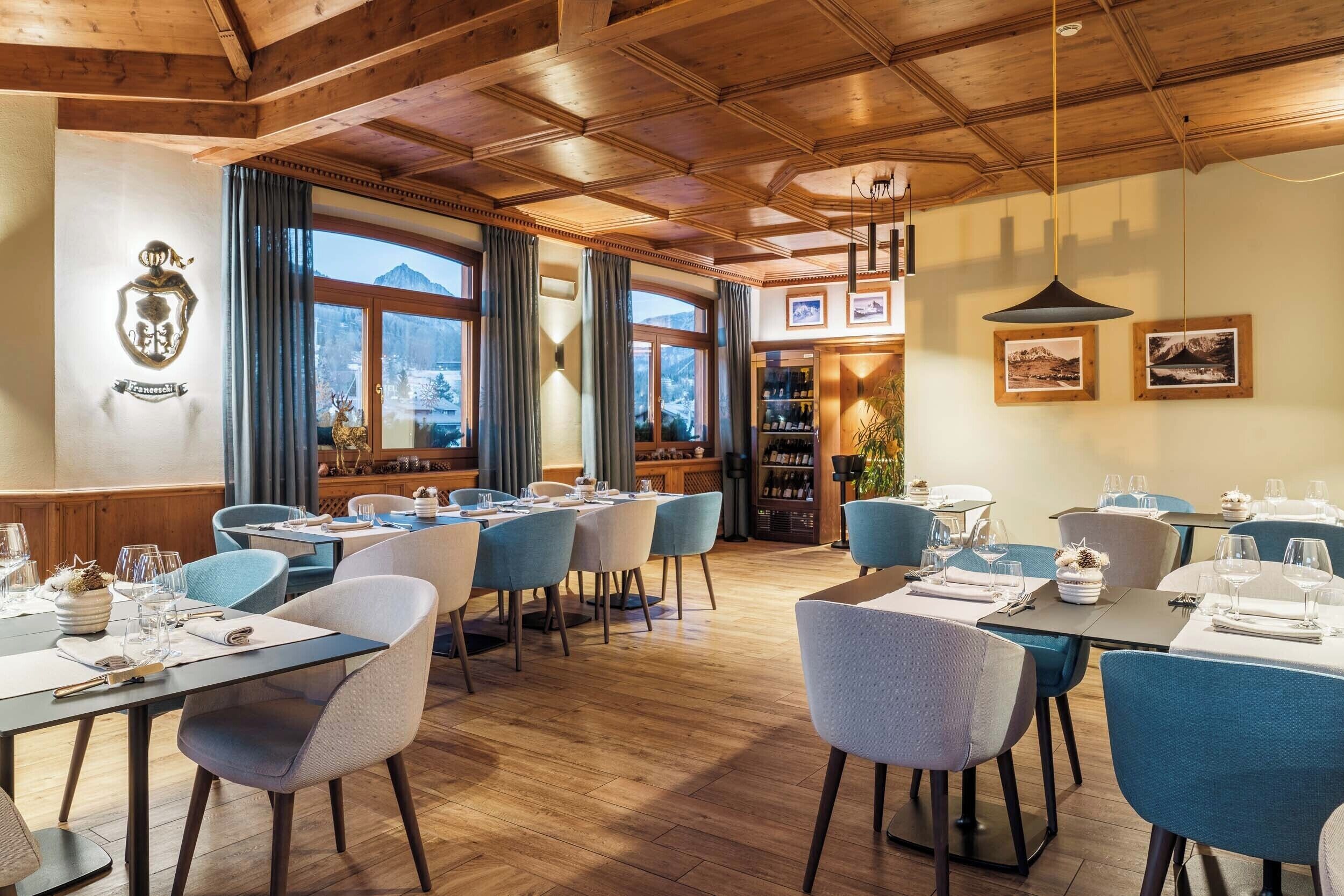 A restaurant with wooden ceilings, blue chairs, and tables set for dining.