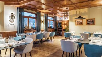 A restaurant with wooden ceilings, blue chairs, and tables set for dining.