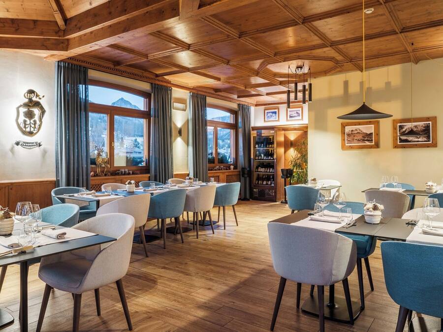 A restaurant with wooden ceilings, blue chairs, and tables set for dining.