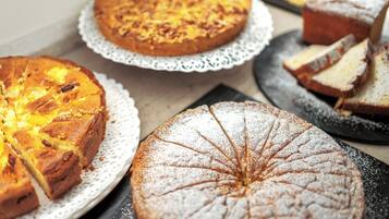 A variety of cakes on different plates, some with powdered sugar.