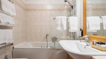 A bathroom with a bathtub, a sink, and a mirror. There are towels hanging on a rack.