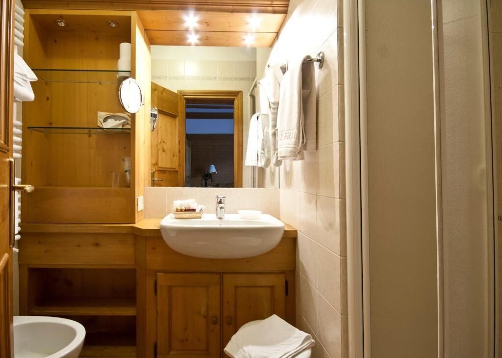 Un baño de madera pequeño y funcional con lavamanos, espejo y toallero.