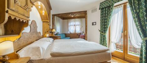 Dormitorio con estructura de madera, cama, mesita de noche y ventana con cortinas.