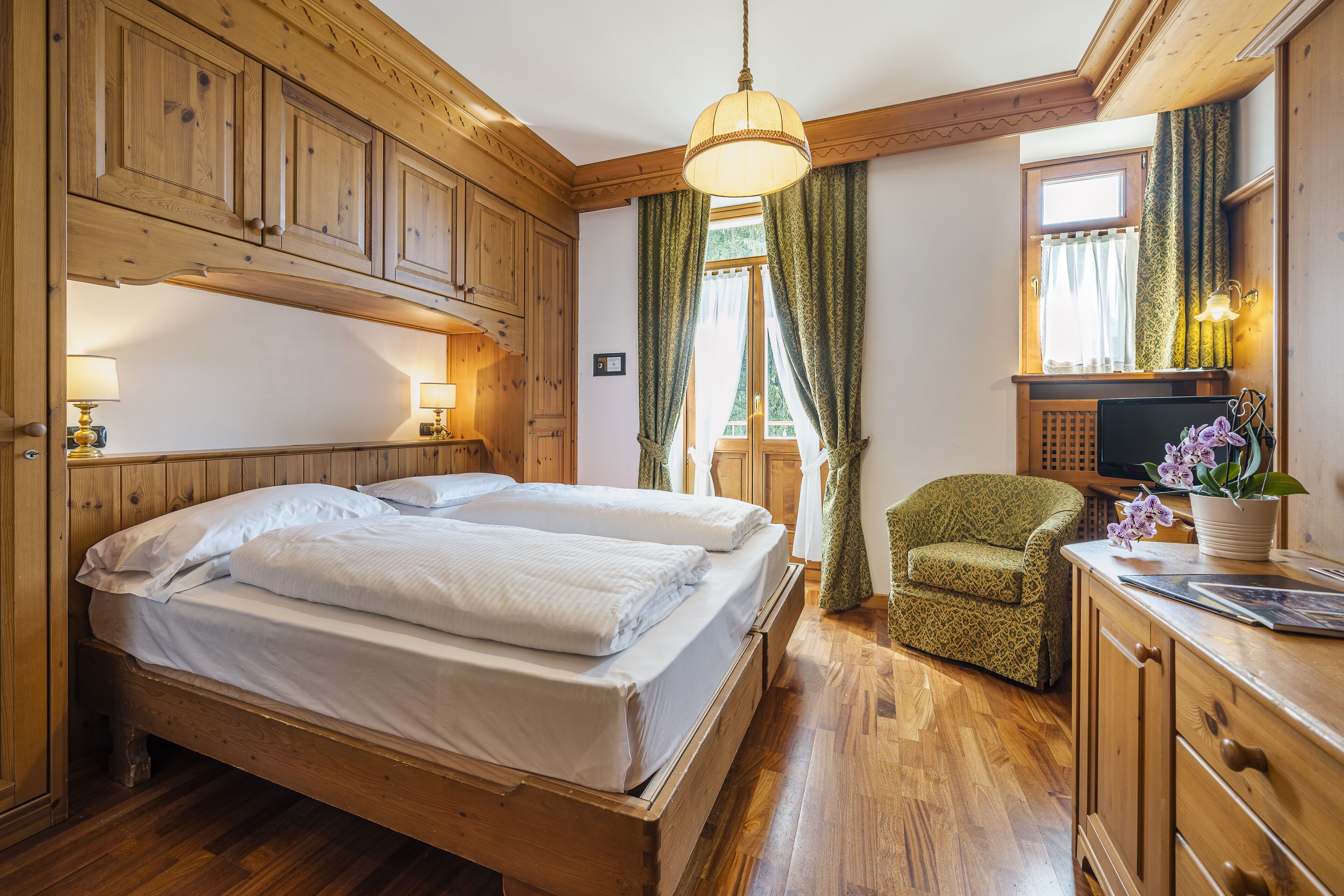 Een houten kamer met twee bedden, een stoel, een bureau en een televisie.