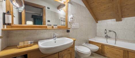 A bathroom with a wooden vanity, a large mirror, a sink, a toilet, and a bathtub.