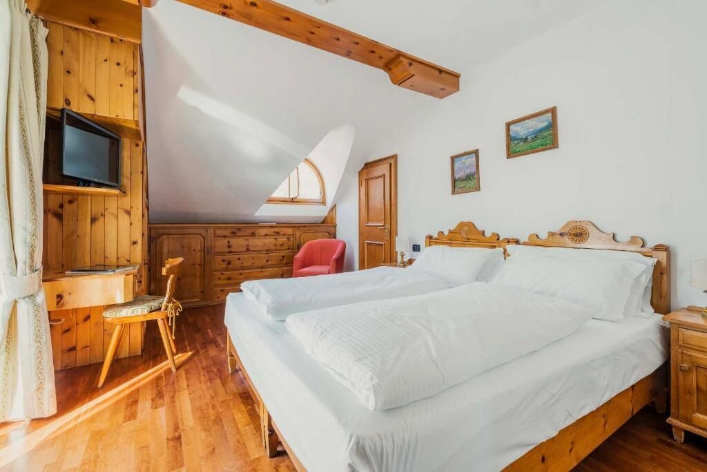 A wooden room with a bed, a desk, and a chair.
