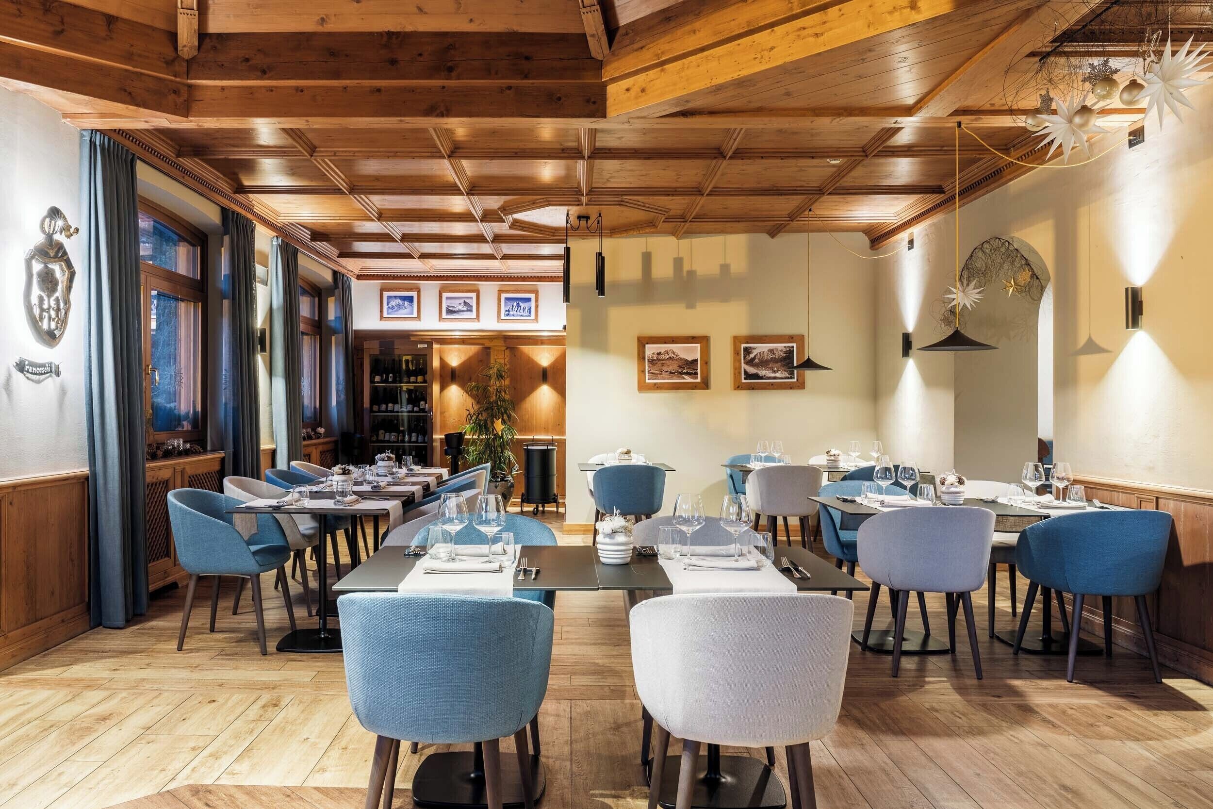Ein Restaurant mit Holzbalkendecke, blauen Stühlen und gedeckten Tischen.