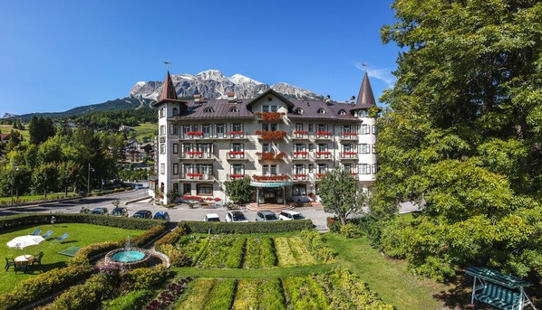 Ein mehrstöckiges Hotel mit Innenhof, umgeben von üppiger Vegetation und Blick auf die Berge.