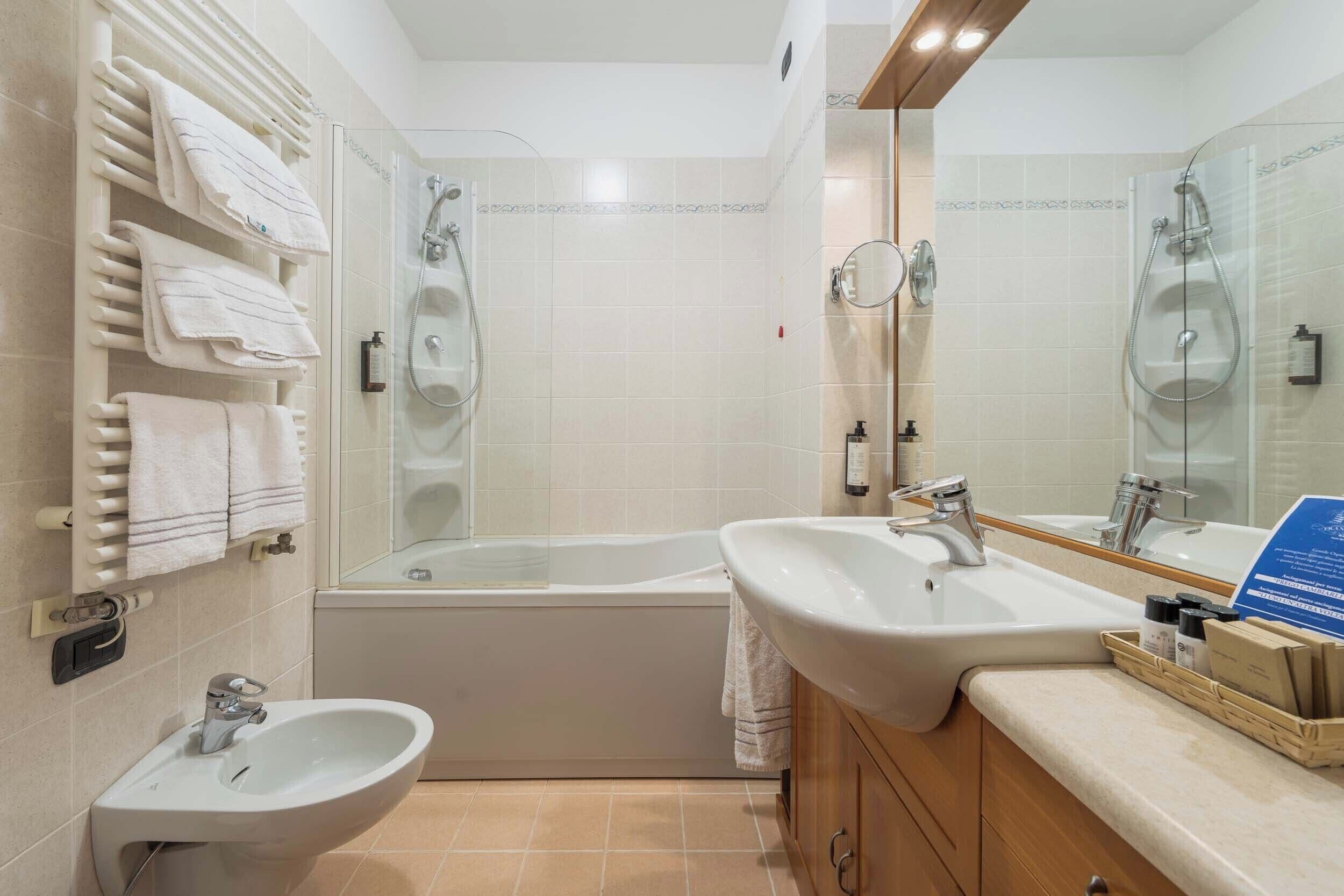Un baño moderno con bañera, dos lavamanos, un bidé y un perchero para toallas.