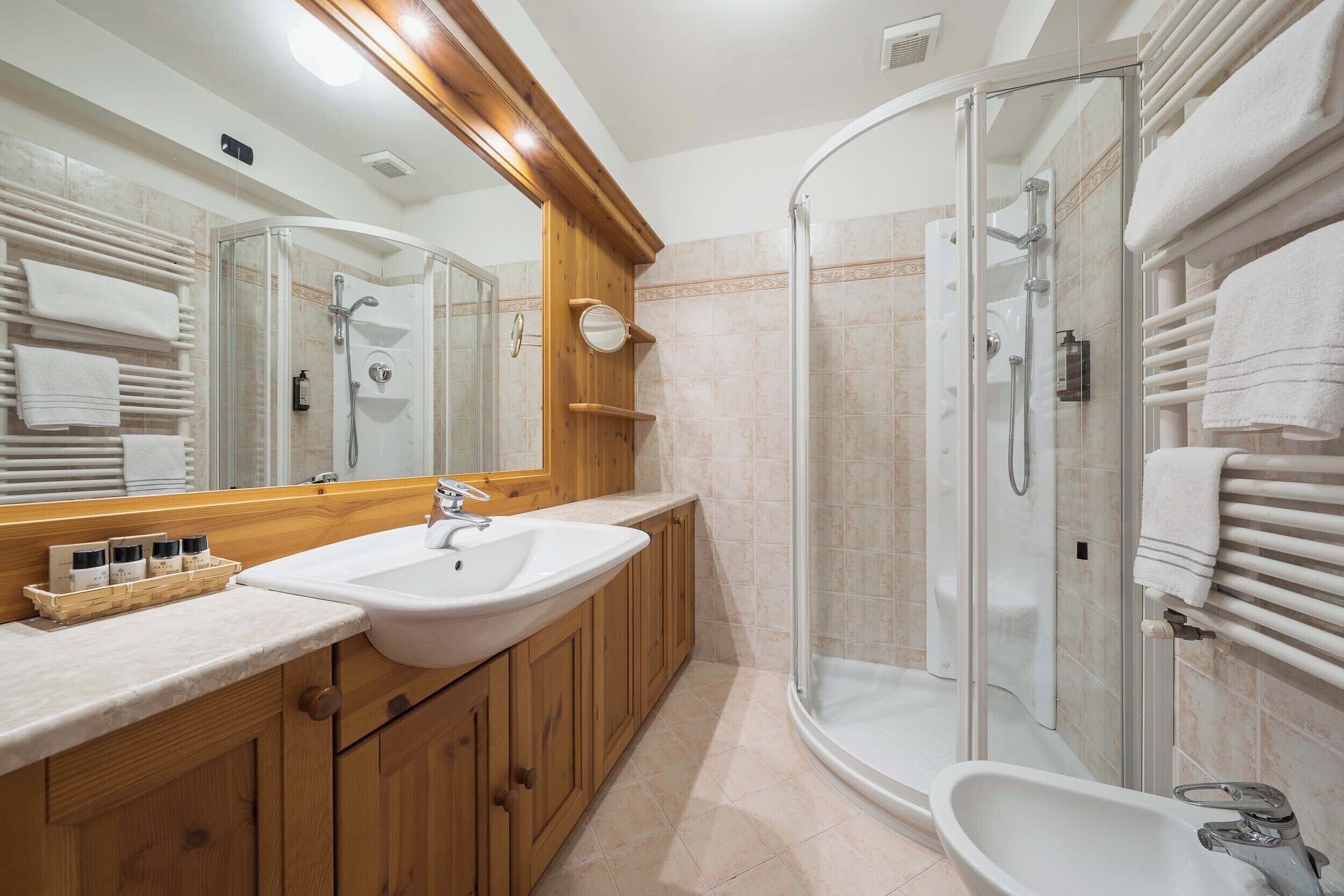 Un baño moderno con ducha de vidrio, lavamanos grande y armarios de madera.