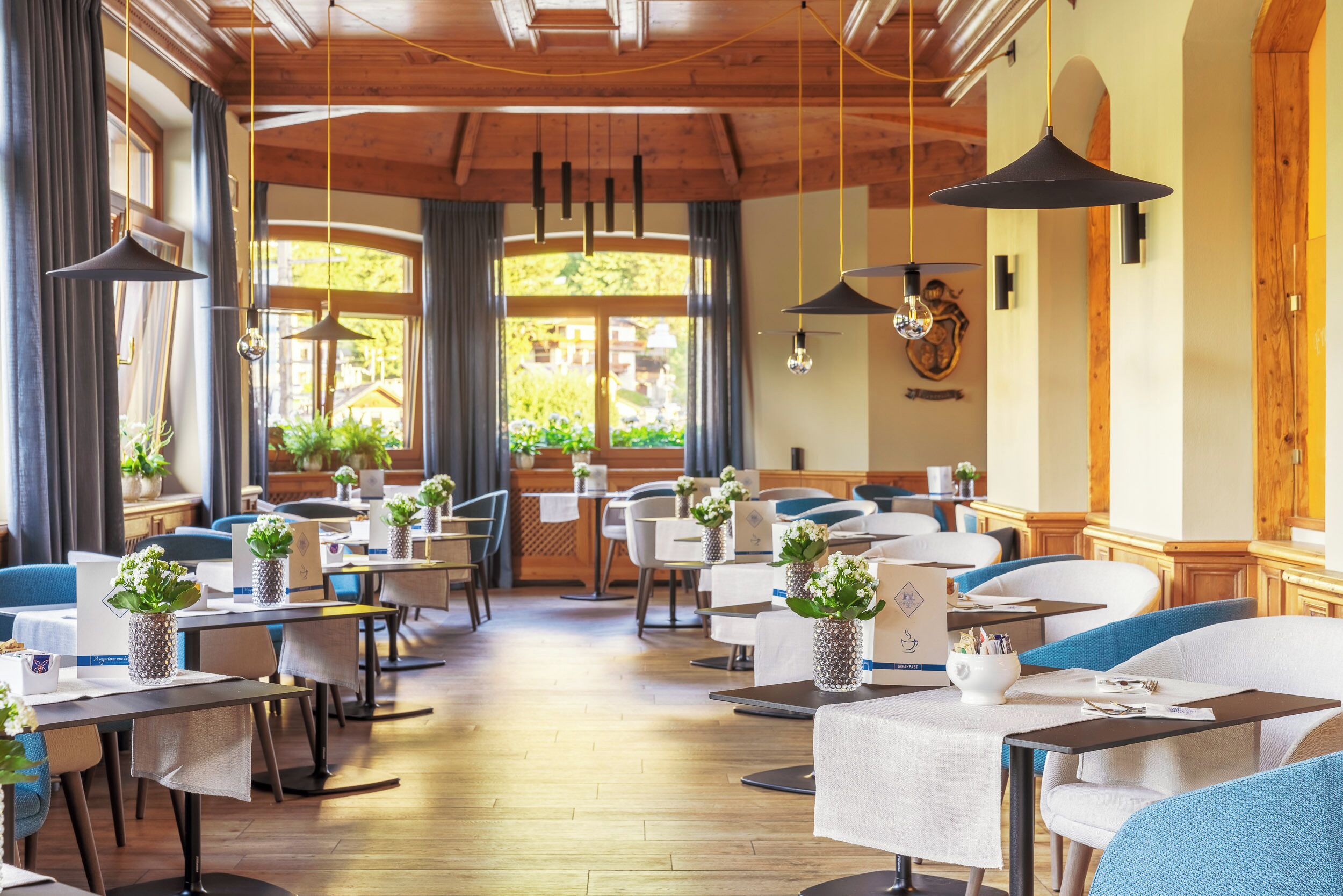 Un restaurante con techos de madera, mesas con manteles blancos y sillas azules.