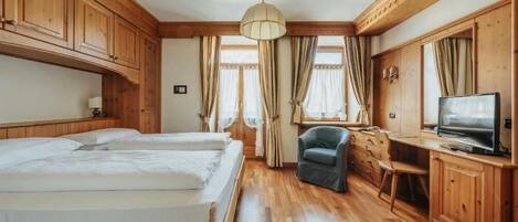 Una habitación con dos camas, un escritorio, una silla, un televisor y armarios de madera.