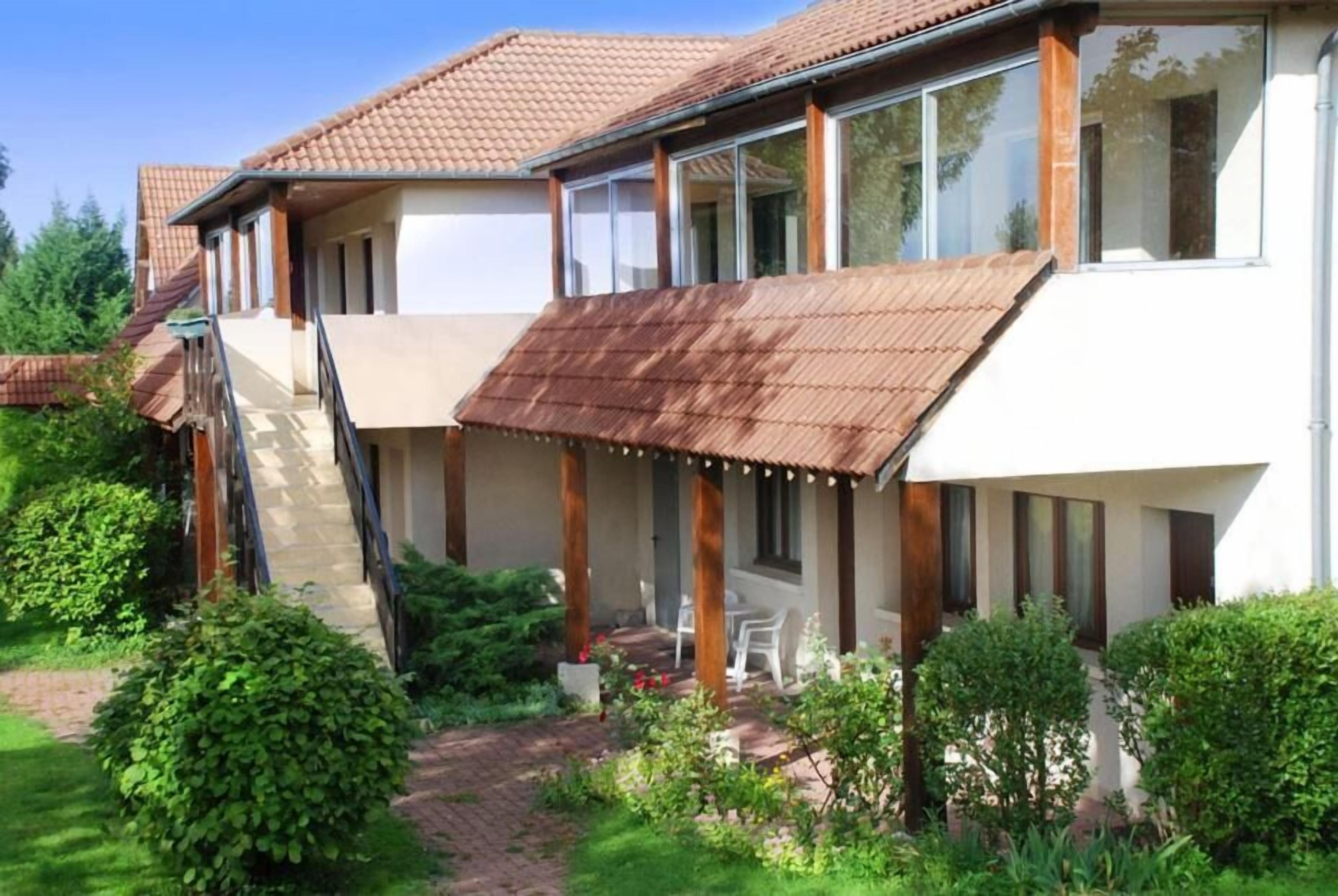 A two-story house with a covered patio, a staircase, and a garden area.