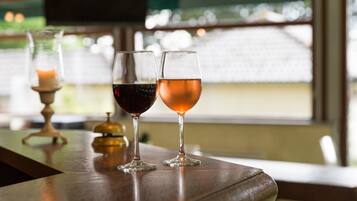 Two wine glasses on a wooden table with a candle and a bell in the background.
