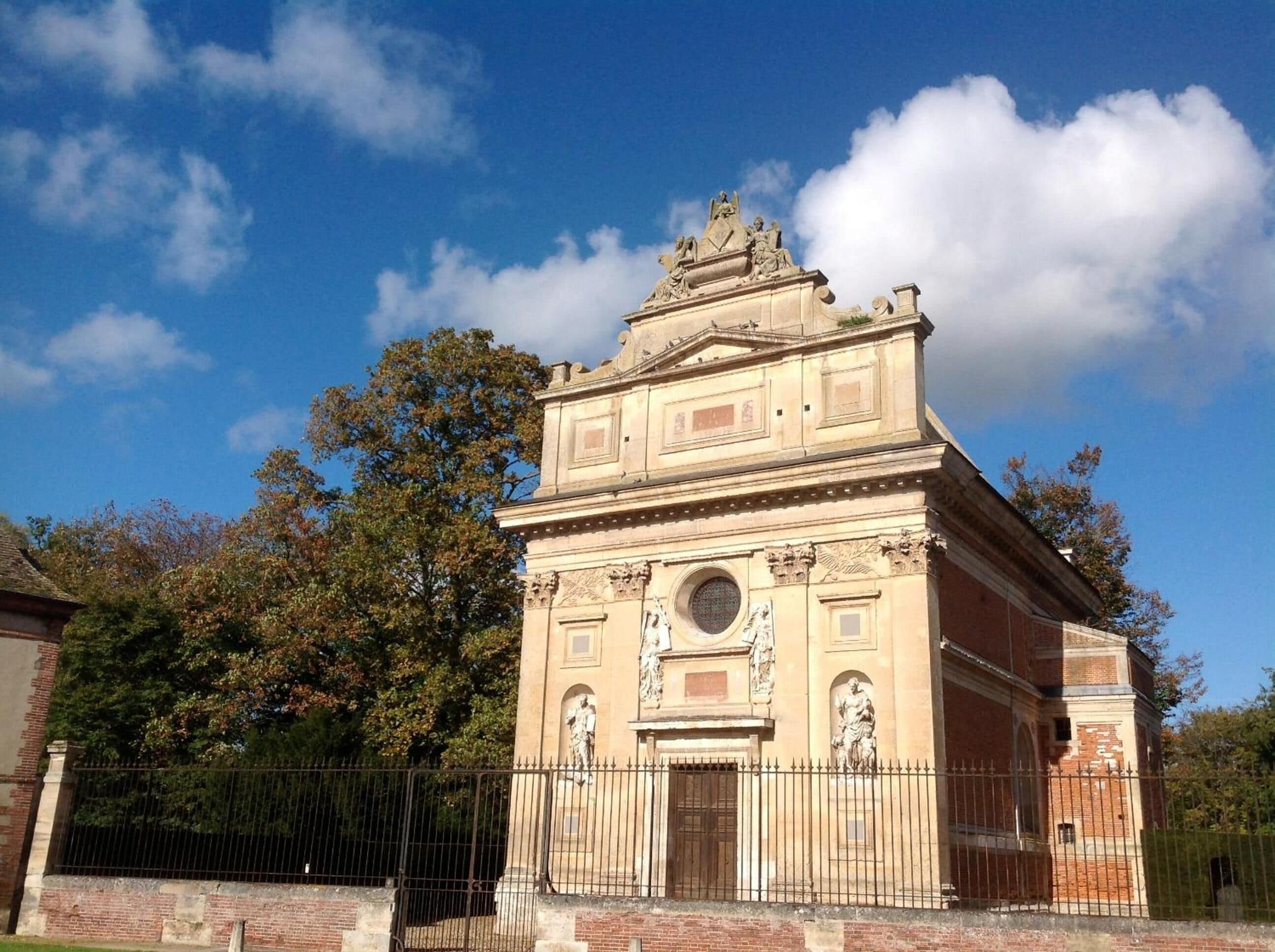 A historic building with a central dome, flanked by statues and intricate carvings.