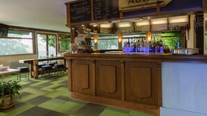 Een bar met een houten toonbank, een krijtbordmenu en uitzicht op de omgeving door grote ramen.