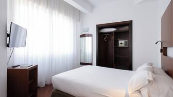 A hotel room with a bed, a TV, a wardrobe, and a mirror.