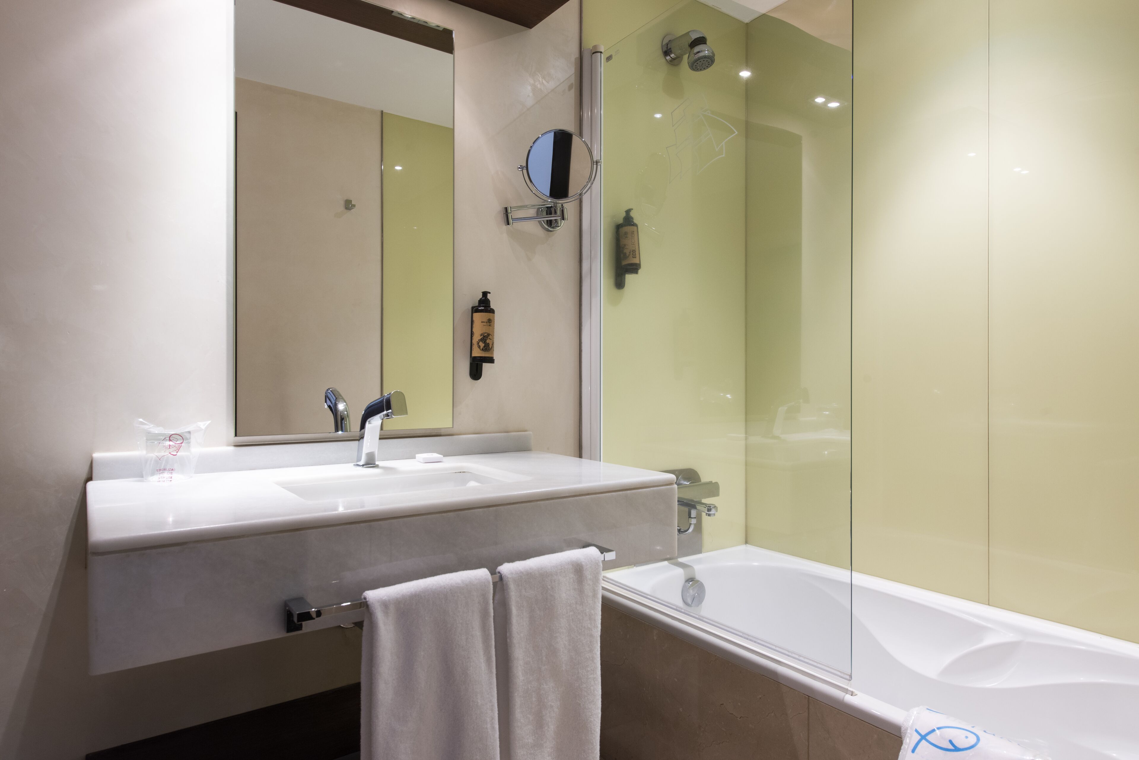 A bathroom with a white sink, a mirror, a towel, and a bathtub.