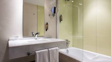 Un baño con lavamanos blanco, espejo, toalla y bañera.