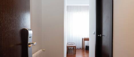 A hallway with a wooden floor, a radiator, a table, and a door.