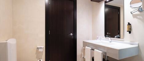 A modern bathroom with a toilet, sink, and mirror.