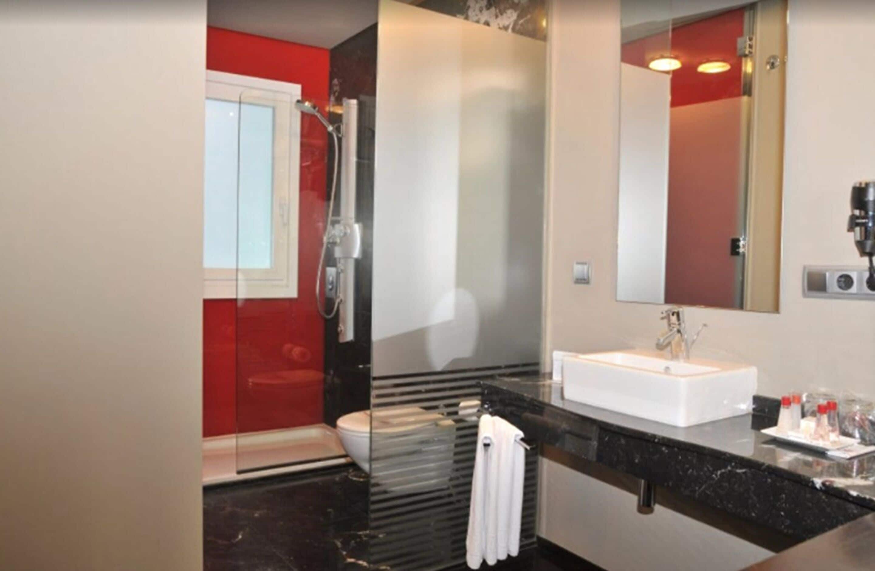 A modern bathroom with a glass shower enclosure, a white sink, and a large mirror.