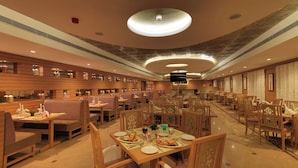 Un restaurante espacioso con cabinas y mesas de madera, un techo alto con iluminación circular y un diseño moderno.