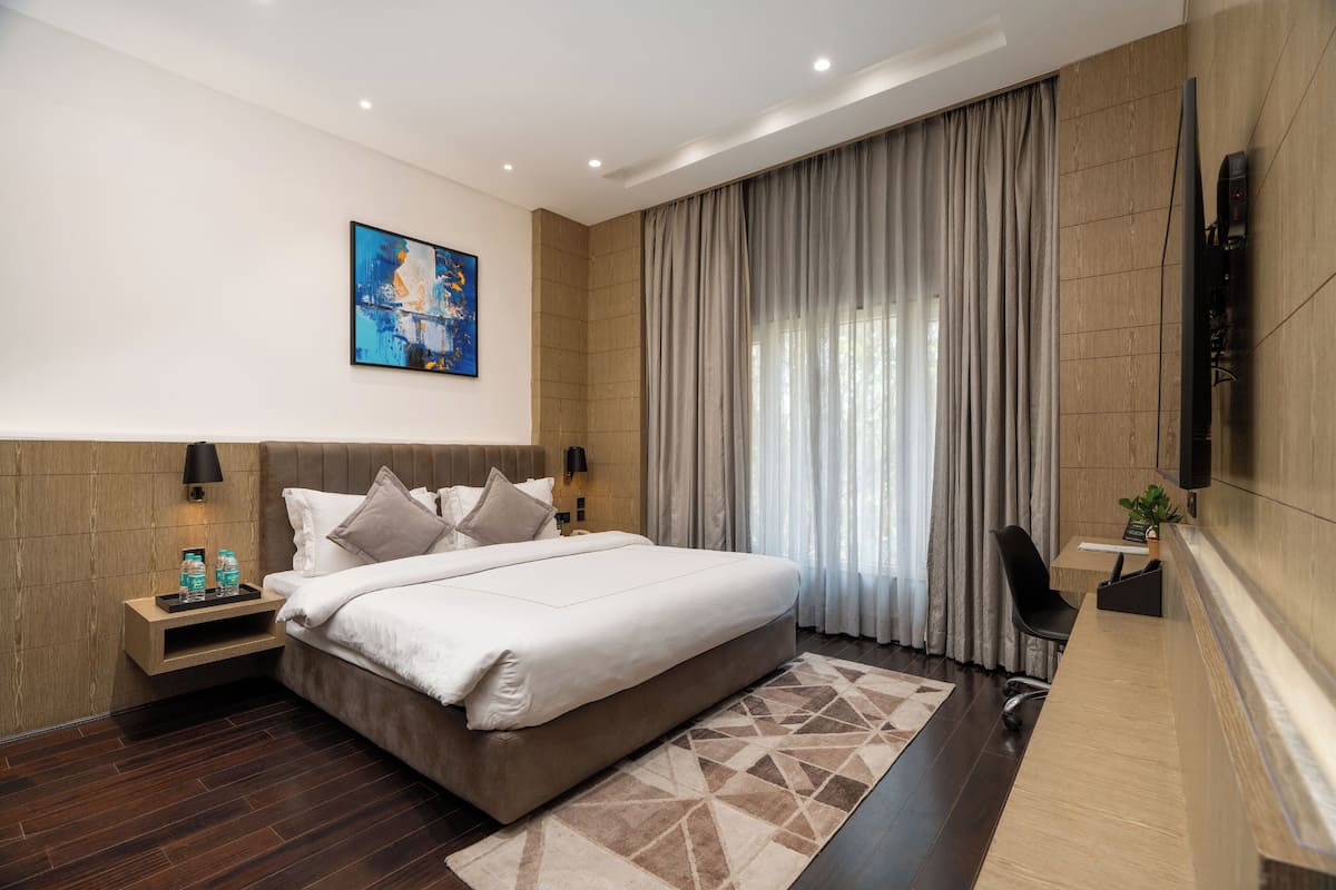 Una habitación de hotel moderna con una cama grande, un escritorio, un televisor de pantalla plana y un cuadro en la pared.