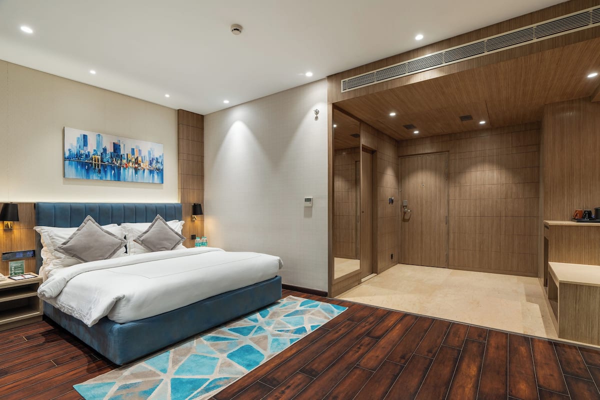Una habitación de hotel moderna con una cama grande, una mesita de noche, un escritorio y zona de ducha.