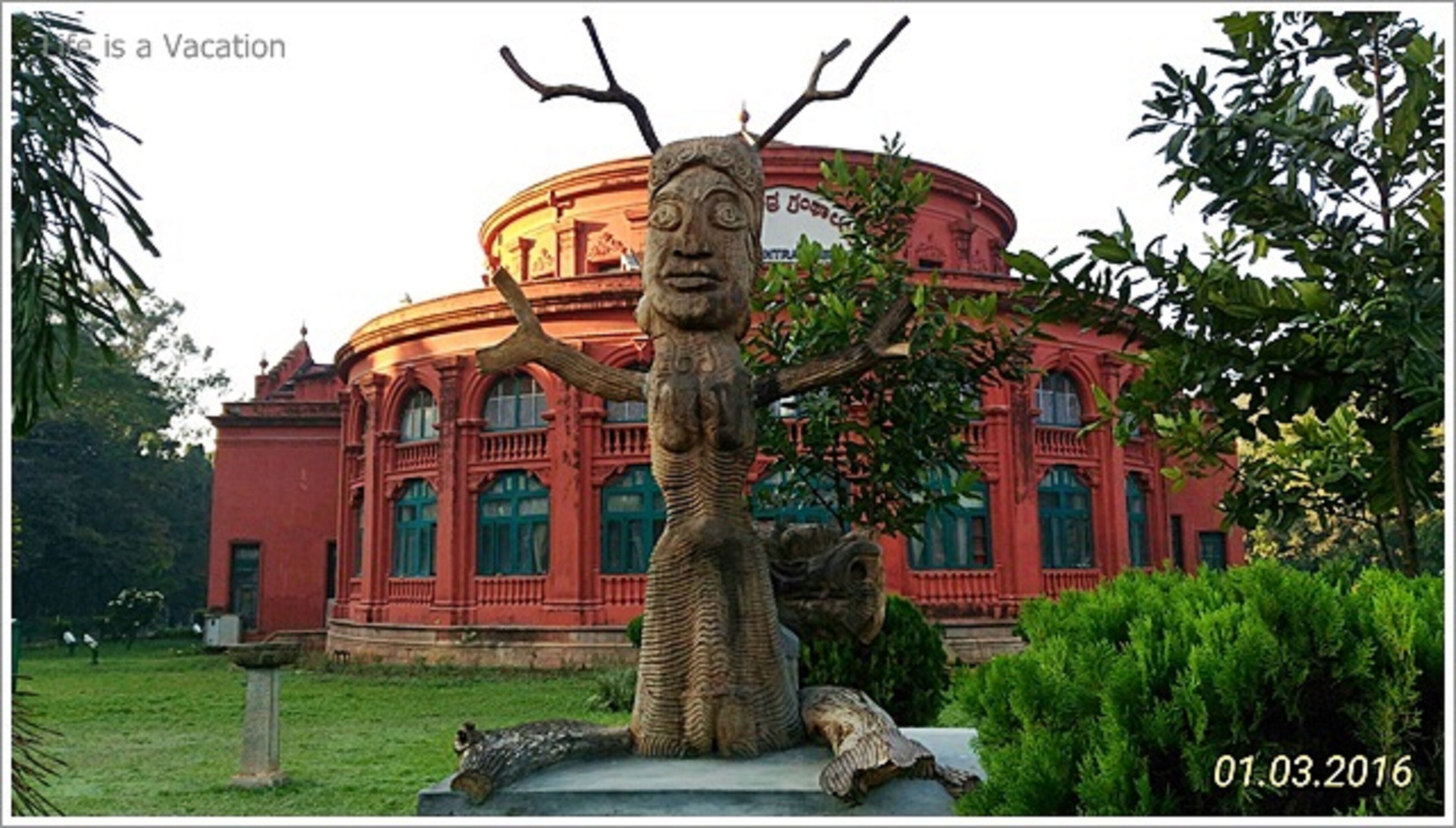 Un bâtiment à la façade circulaire, orné d’une sculpture représentant un arbre et une figure humaine.