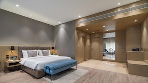 Un dormitorio moderno con una cama grande, mesitas de noche, un escritorio y vistas al área de estar.