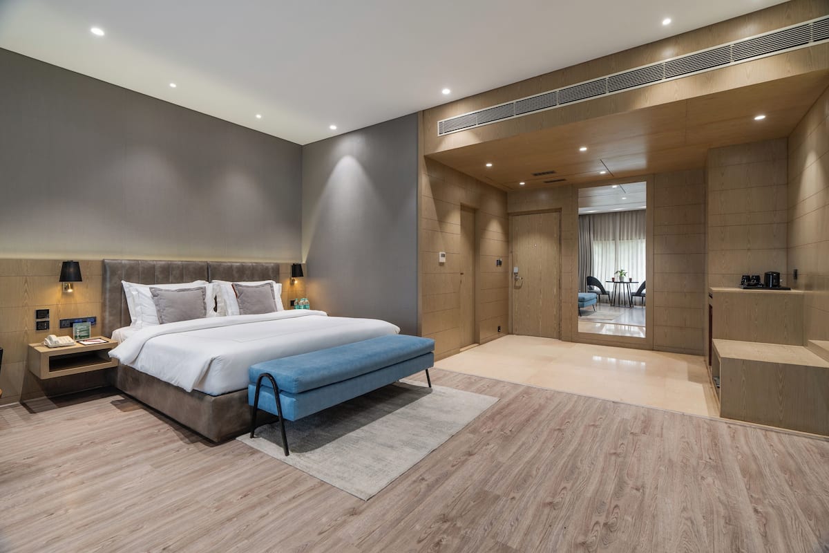Un dormitorio moderno con una cama grande, mesitas de noche, un escritorio y vistas al área de estar.