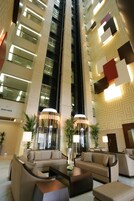 A modern lobby with a high ceiling, a central seating area, and a patterned wall design.