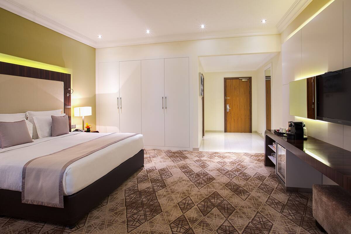 A modern hotel room with a large bed, wardrobe, and a TV.