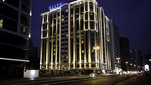 Un hotel de varios pisos con señalización iluminada, una entrada destacada y una fachada bien iluminada.