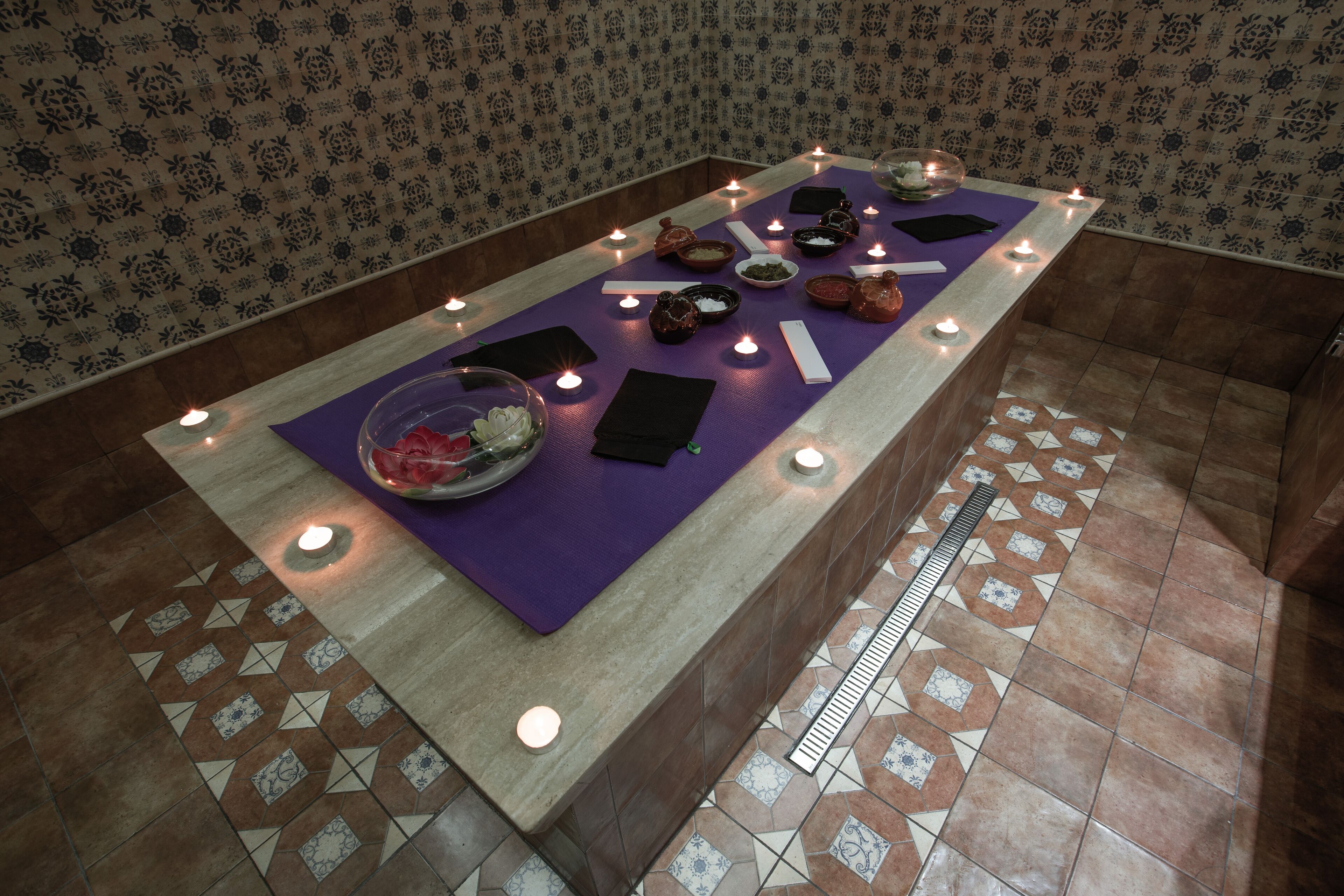 Un área de spa con un largo banco, velas y diversos productos de spa.