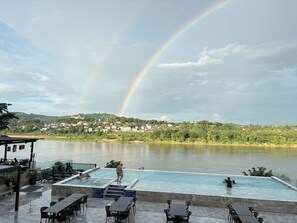 A pool area with a view of a river and a rainbow. - Chiangkhong Teak Garden Riverfront Hotel (Chiang Khong)