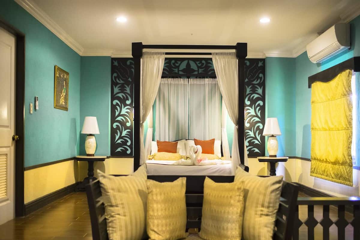 Un dormitorio con cama con dosel, dos mesitas de noche con lámparas y vista al cuarto.