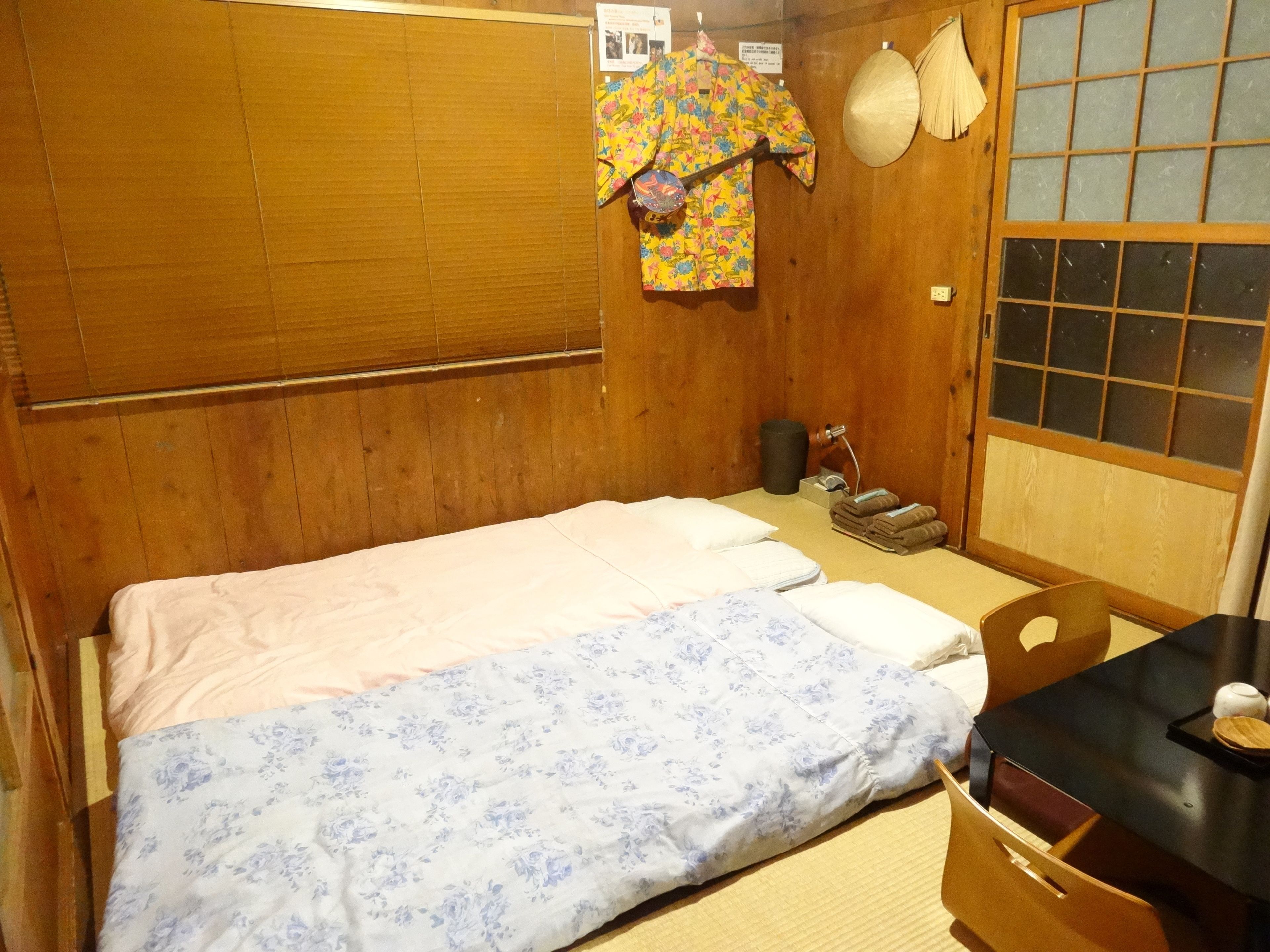 Um quarto japonês tradicional com cama, paredes de madeira, esteira de tatame e um painel shoji.