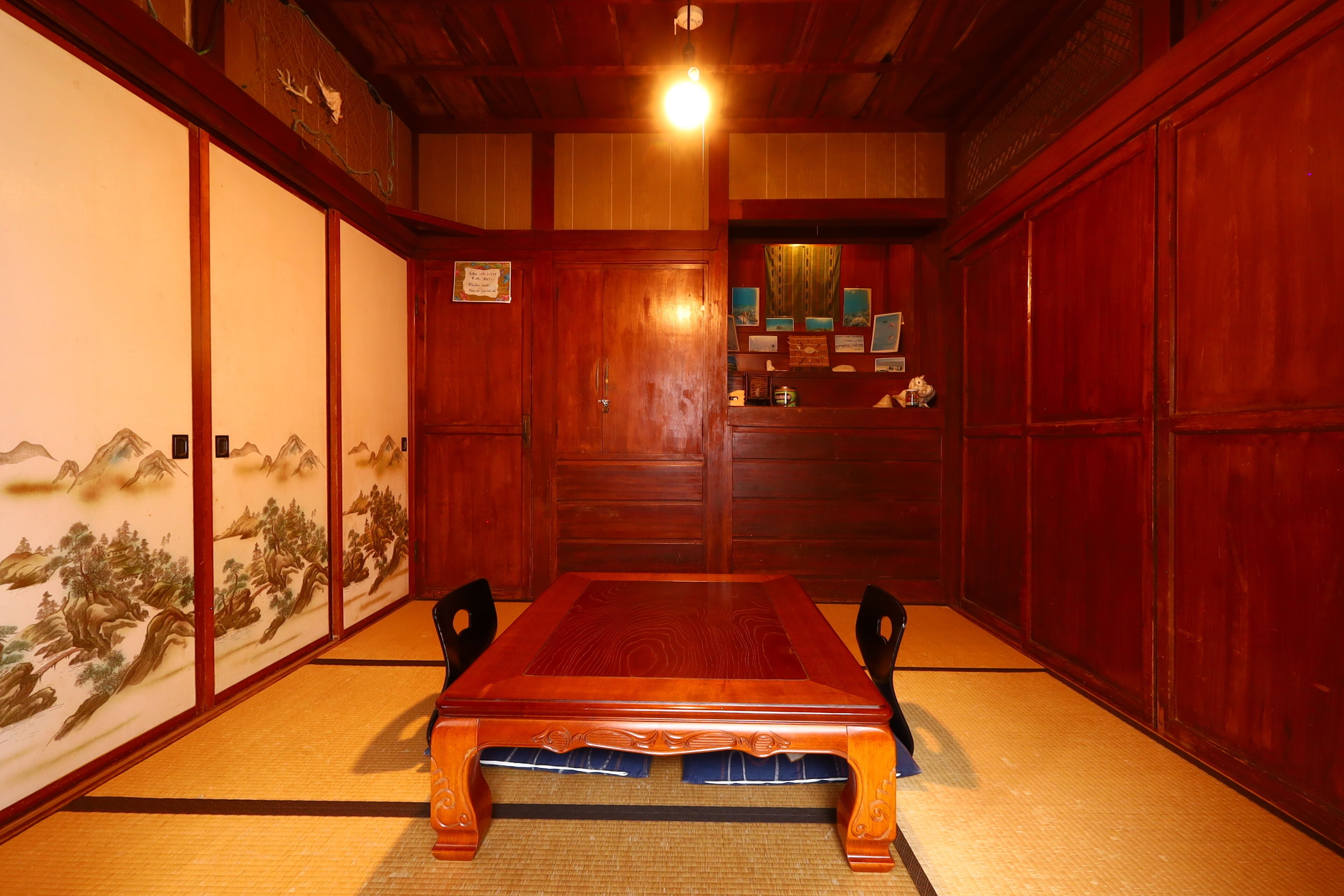 A traditional Japanese room with tatami flooring, a wooden table, and sliding doors with artwork.
