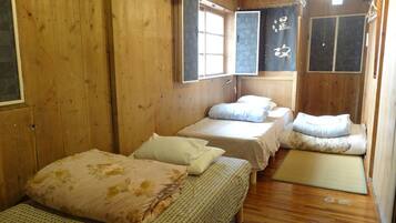 Una habitación de madera con dos camas, una ventana y un futón de tatami.