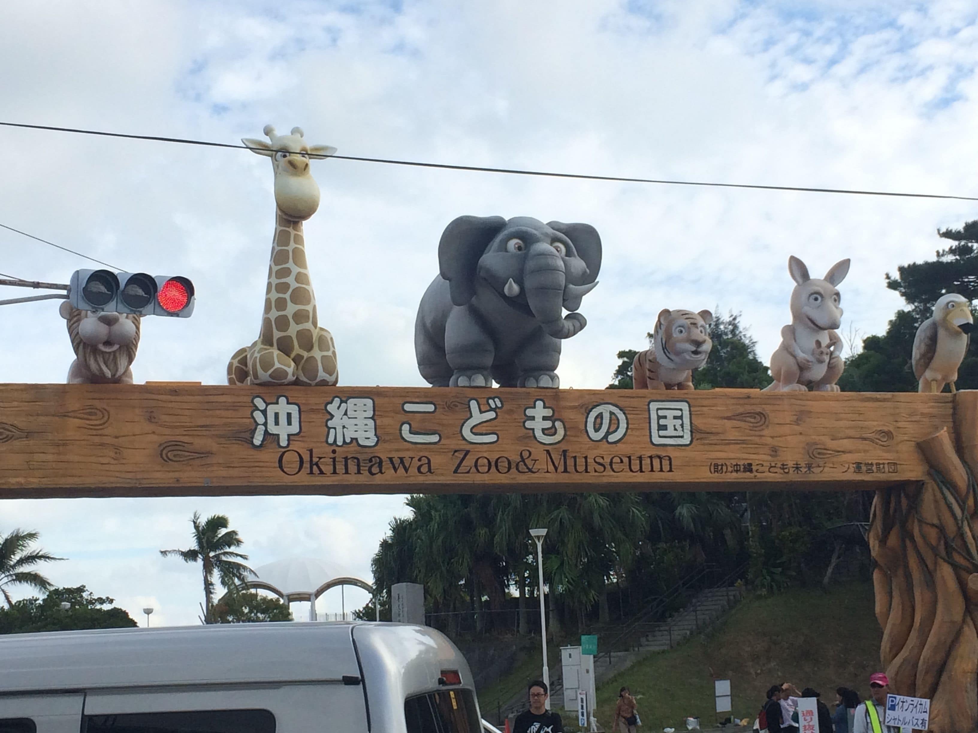 A wooden sign with animal figures and text for Okinawa Zoo & Museum.