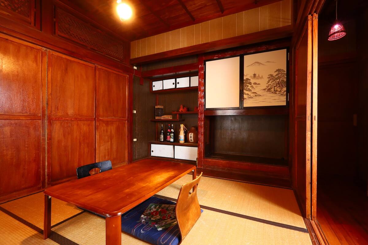 A traditional Japanese room with tatami flooring, a wooden table, and a low seating area.