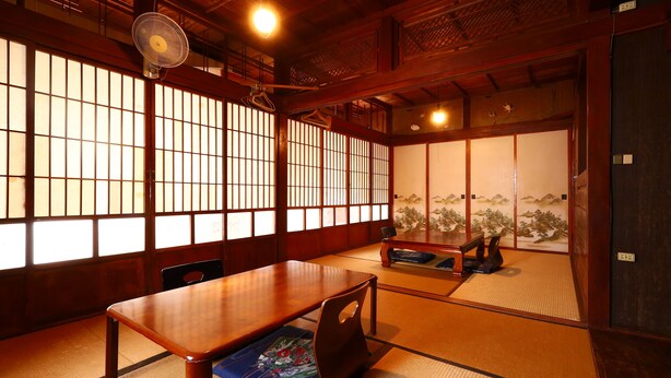 Una habitación japonesa tradicional con suelo de tatami, una mesa de madera baja y puertas correderas.