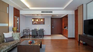 A modern living room with a sofa, coffee table, TV, and a dining area with chairs and a table.