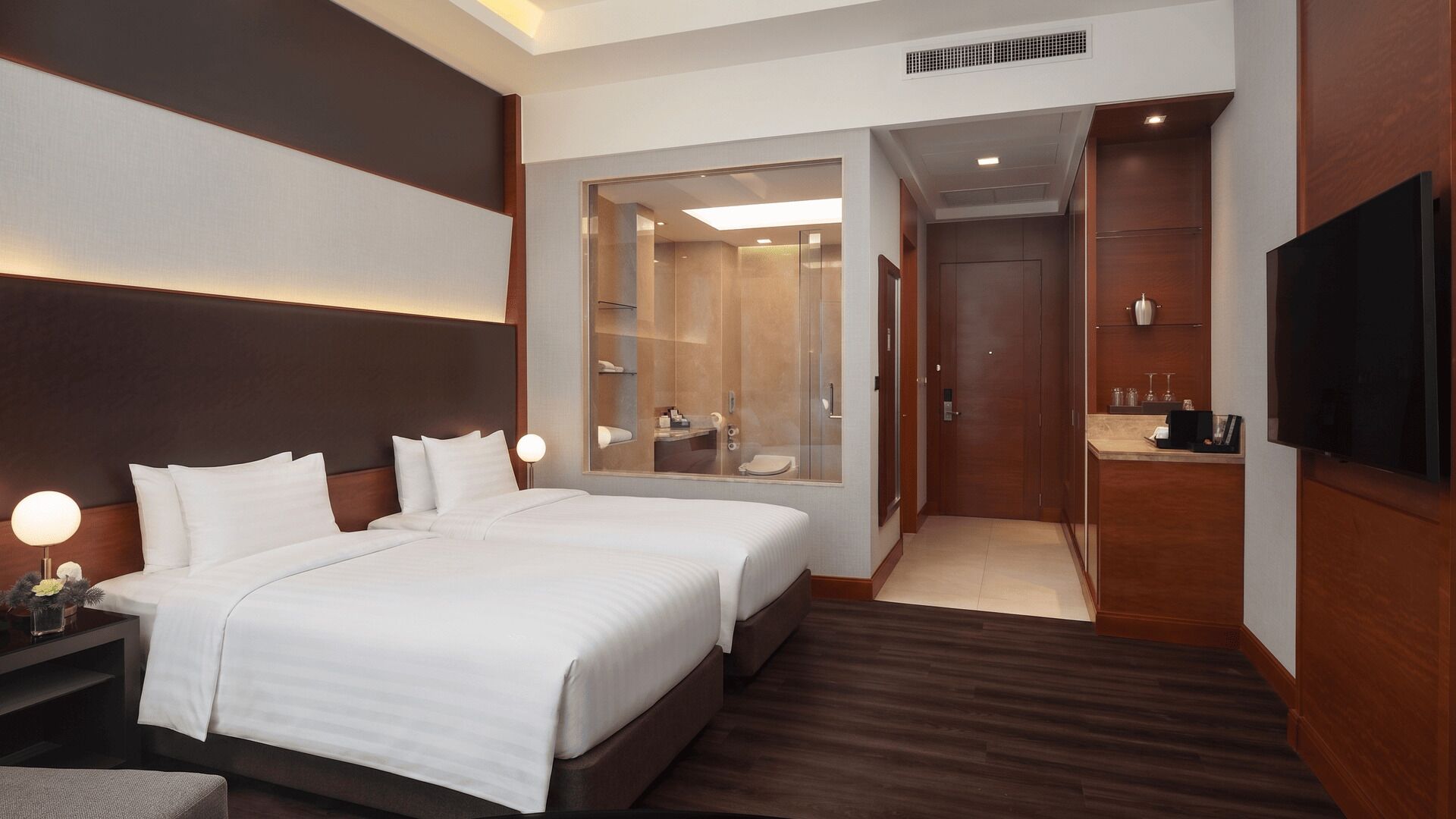 A hotel room with a large bed, a TV, a mirror, and a walk-in closet.